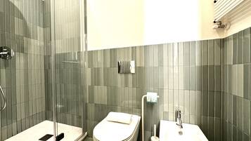 Un bagno con doccia vetro, un water e un lavandino.