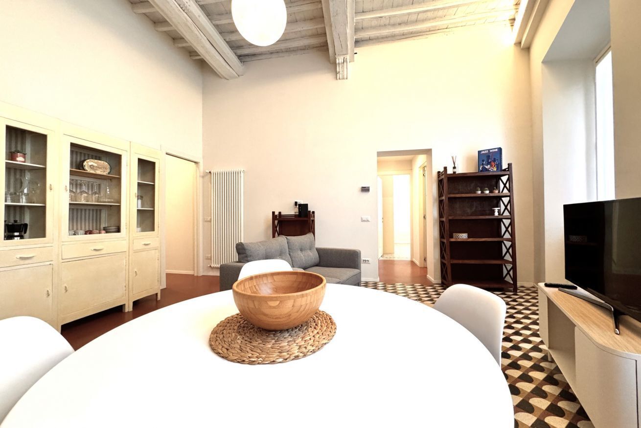A modern living room with a round table, a sofa, a TV, and a cabinet with glass doors.