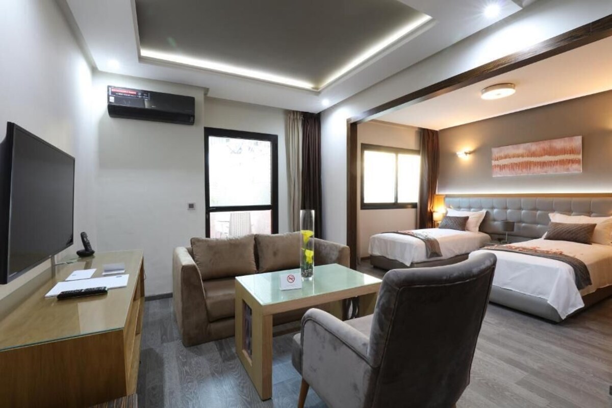 Une chambre d’hôtel équipée d’un téléviseur à écran plat, d’un canapé, d’une petite table, d’un lit et d’une tête de lit.