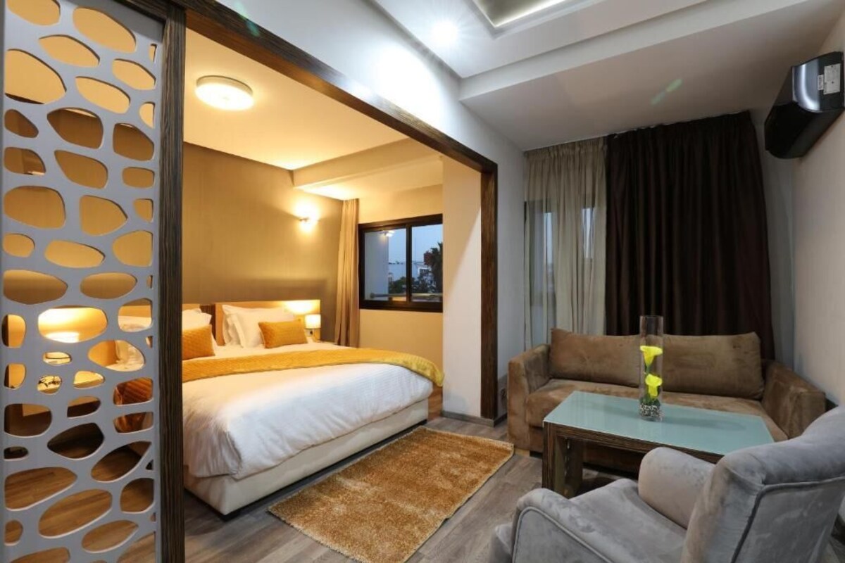 Una habitación de hotel con una cama, un sofá, una mesita de café y una planta decorativa.