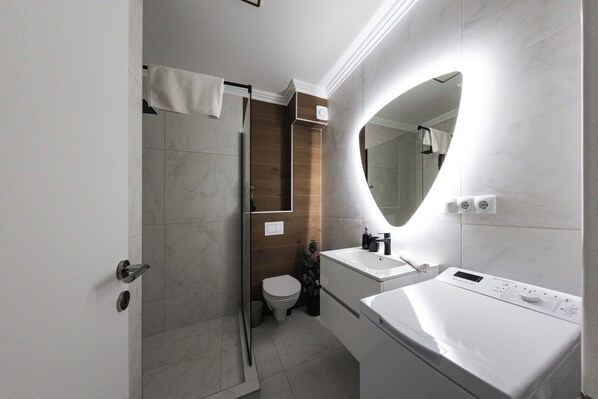 Un baño moderno con ducha, inodoro y dos lavamanos.