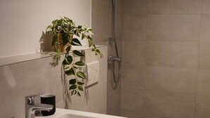 A modern bathroom with a white sink, a toilet, and a shower. - Wine, space & well-being - your vacation apartment "Im Rosengarten - I" (Mommenheim)
