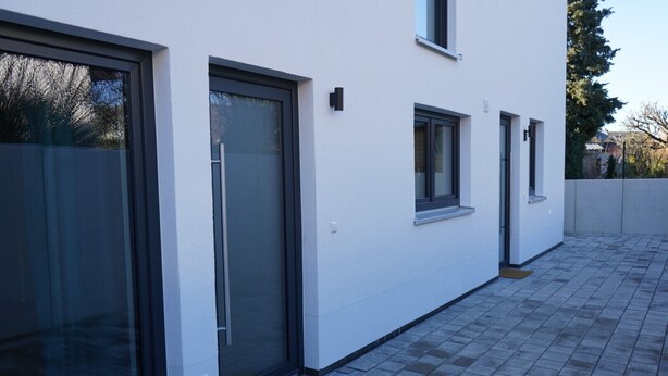 A modern building with large sliding glass doors, a small window, and a tiled patio area. - Wine, space & well-being - your vacation apartment "Im Rosengarten - I" (Mommenheim)