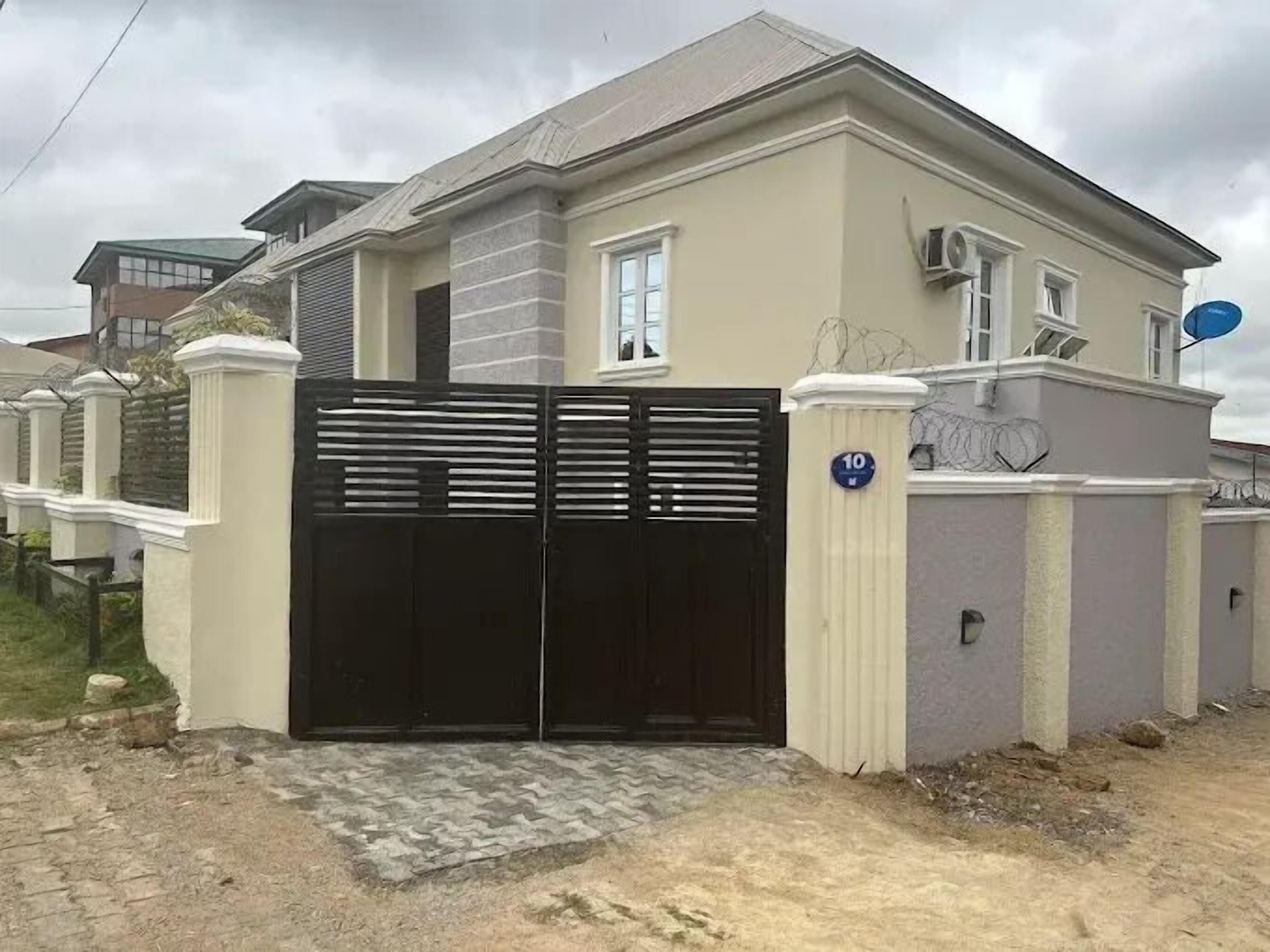 A modern two-story house with a black gate, beige exterior, and a number '10' sign.