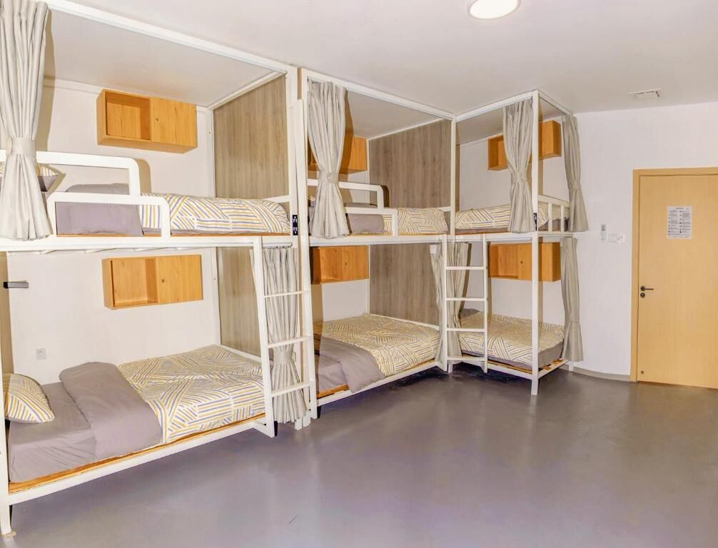A bunk bed room with wooden headboards, curtains, and a door.