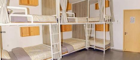 A bunk bed room with wooden headboards, curtains, and a door.
