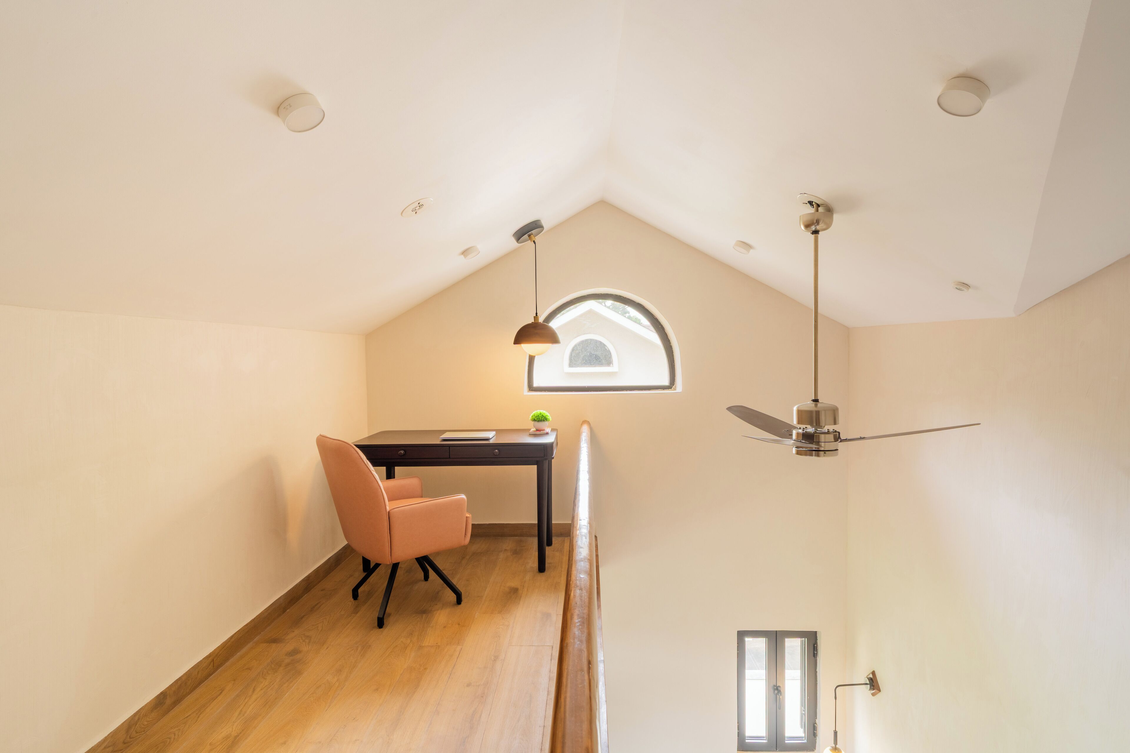 A high-ceilinged room with a desk, chair, and a small window.