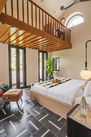 Ein Schlafzimmer mit einem großen Bett, einer Holztreppe, einem Topfpflanzen und Blick ins Freie.