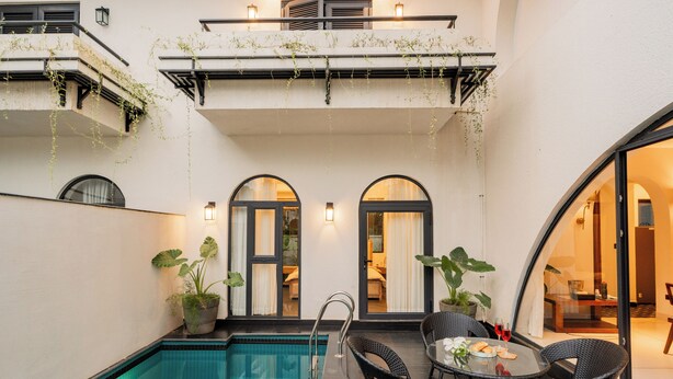 Un espace aménagé au bord de la piscine, comprenant une piscine, des sièges extérieurs et une vue sur l’intérieur du bâtiment.