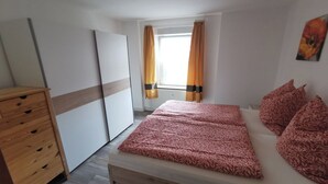 A bedroom with a bed, wooden dresser, and a window with curtains. - Cozy vacation apartment on the outskirts of Pirna in Saxon Switzerland (Pirna)