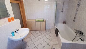 A bathroom with a sink, bathtub, and shower area. - Cozy vacation apartment on the outskirts of Pirna in Saxon Switzerland (Pirna)