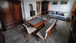 A dining area with a wooden table and benches, a sofa, and a cabinet. - Cozy vacation apartment on the outskirts of Pirna in Saxon Switzerland (Pirna)