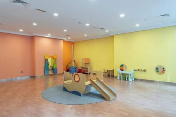 A spacious room with a play area featuring a slide and climbing structures.