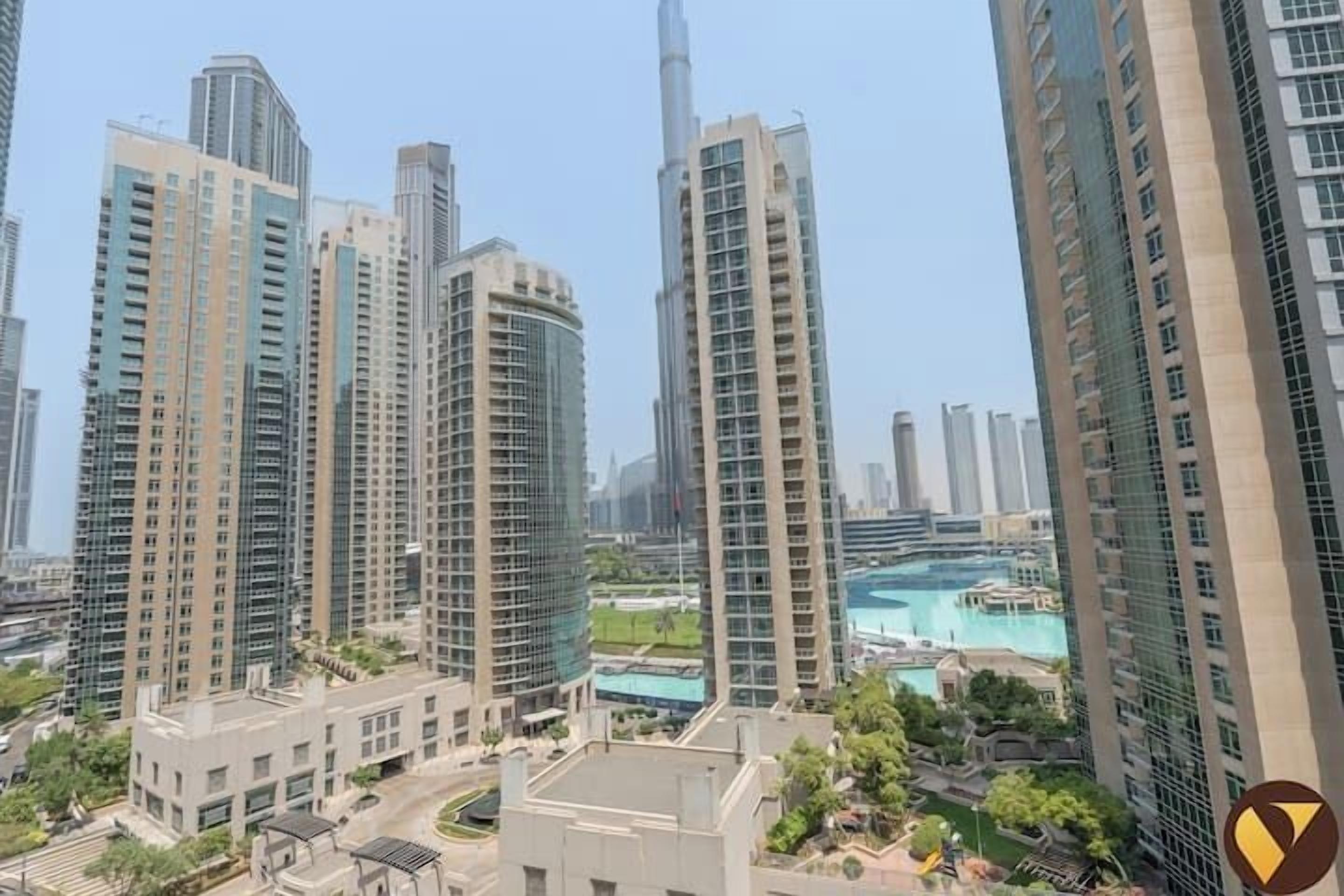 A high-rise residential building complex with multiple apartment buildings, a central courtyard, and a view of a large body of water.