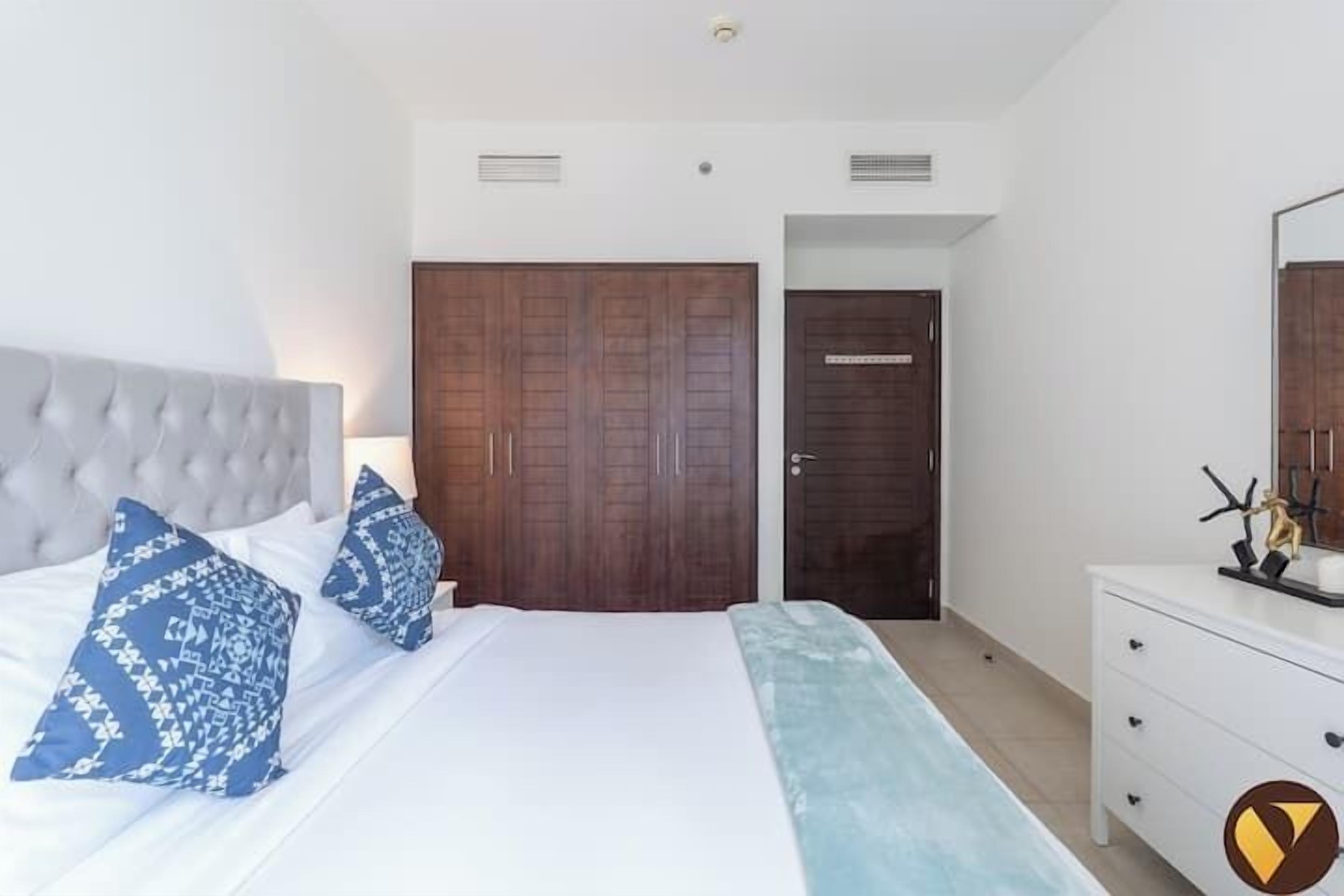 Een slaapkamer met een groot bed, een kledingkast, een dressoir en een spiegel.