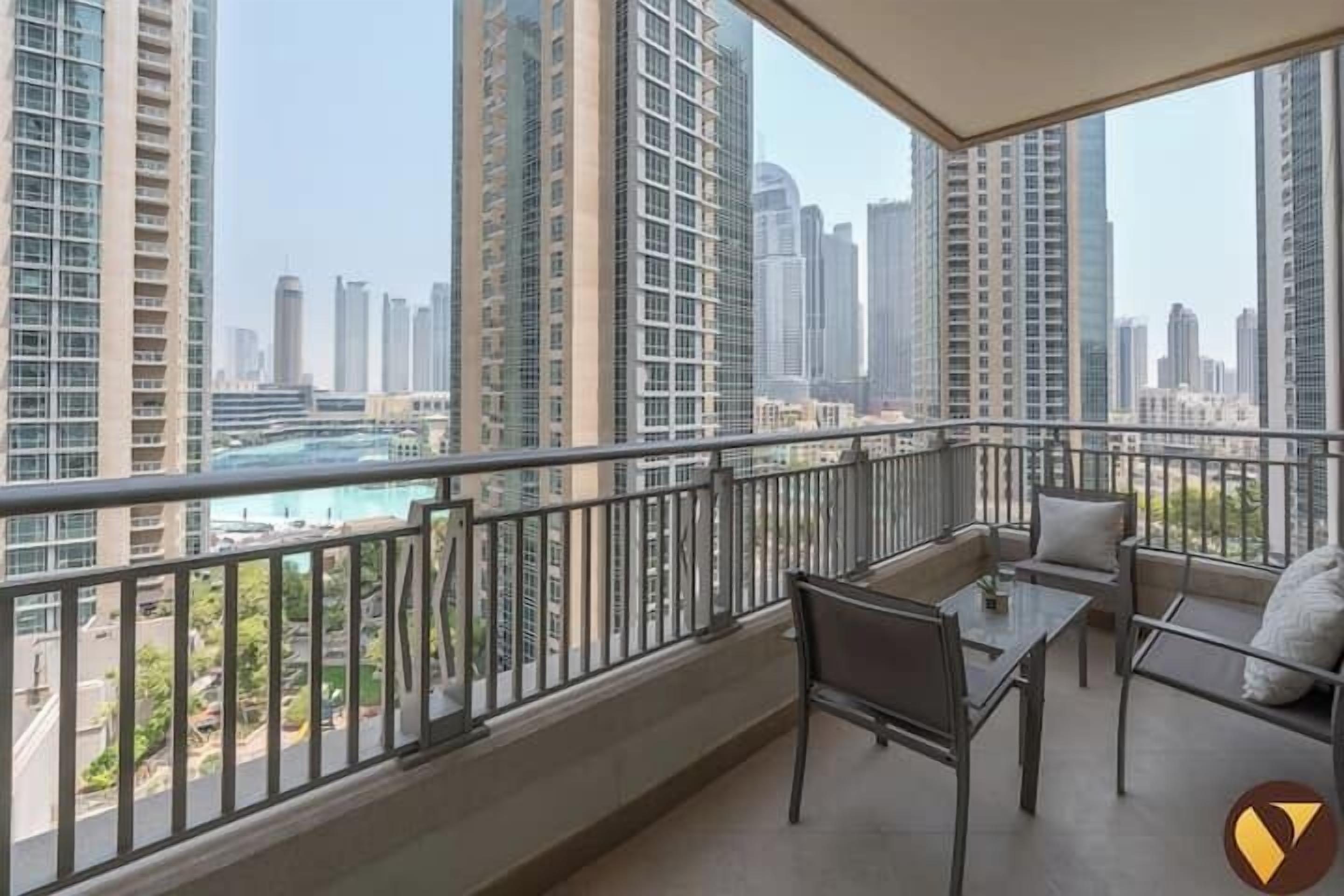 A balcony with a view of tall buildings and a swimming pool.