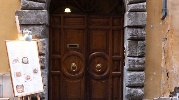 A wooden double door with a circular handle, set within a stone archway.