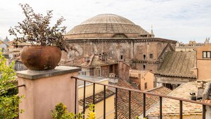 A domed building with a tiled roof, surrounded by other buildings.