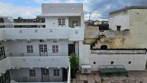 Un immeuble à plusieurs étages doté d’un balcon, d’un pot de fleurs et d’un banc.