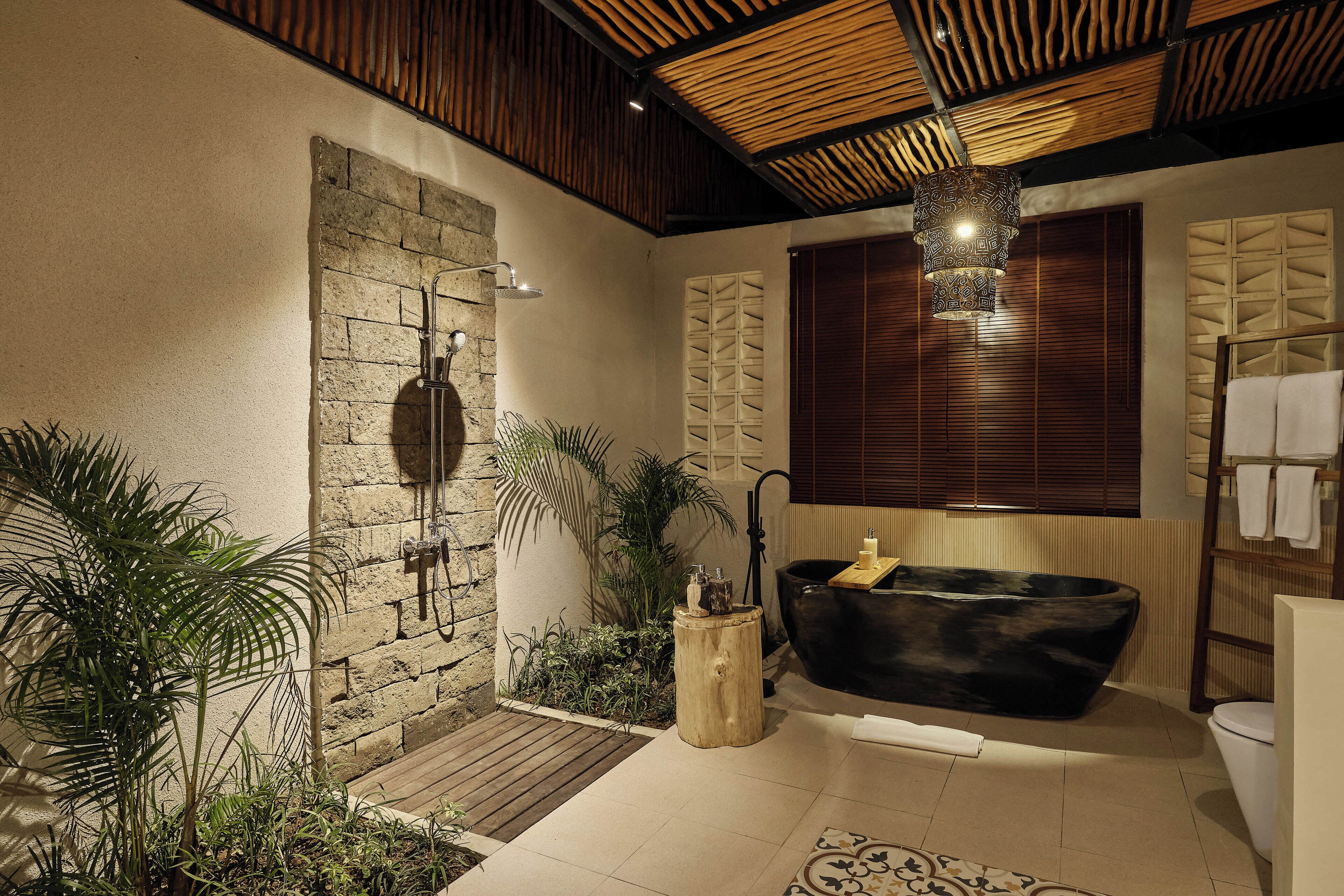 A modern bathroom with a stone shower, a black bathtub, and a wooden ceiling.