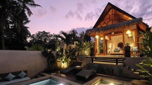A resort with a pool, lounge chairs, and a thatched-roof structure. - Changi Jungle Ubud Villas (Ubud)