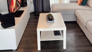 A living room with a flat-screen TV, a white coffee table, a sofa, and a potted plant. - Boathouse Amsterdam with bikes (Amsterdam)
