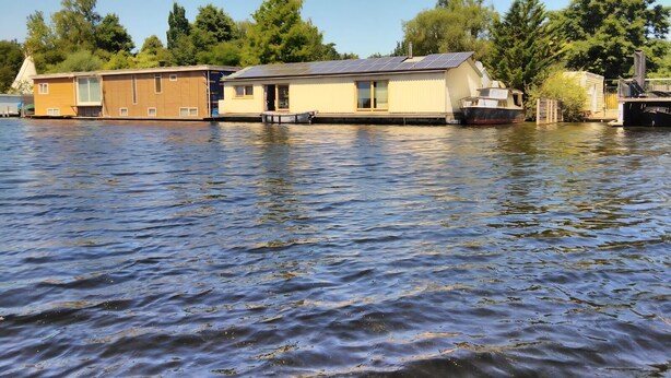 A floating house with a metal roof, a dock, and a boat. - Boathouse Amsterdam with bikes (Amsterdam)