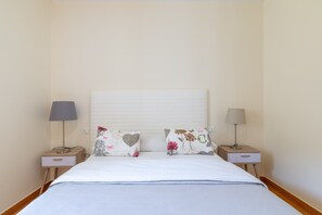Une chambre à coucher avec un lit, deux tables de chevet et deux lampes.