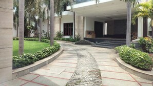 A modern building with a curved pathway, palm trees, and a well-maintained garden. - Truliv Villa Nova (Chennai)
