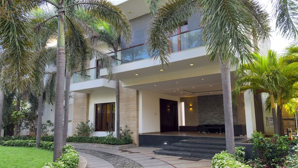 A modern two-story building with a curved pathway leading to the entrance, surrounded by palm trees and well-maintained greenery. - Truliv Villa Nova (Chennai)