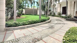 A courtyard with a curved pathway, palm trees, and a well-maintained lawn. - Truliv Villa Nova (Chennai)