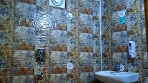 A bathroom with patterned tiles, a sink, and a blue bucket. - Shree Ji Inn Homestay (Rishikesh)