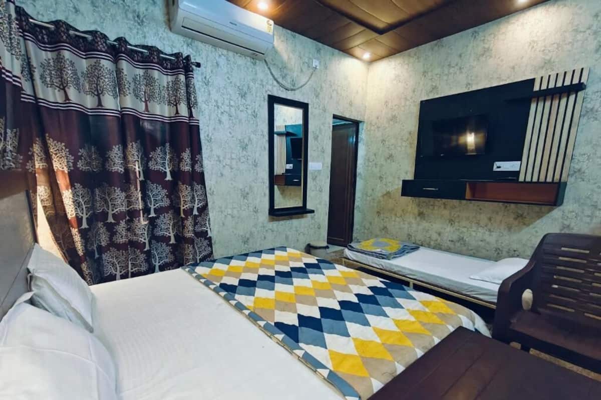 A room with a bed, a small table, a TV, and a mirror.