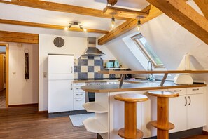 A modern kitchen with a checkered backsplash, a built-in oven, and a window above the sink.