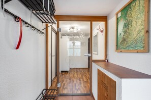 A hallway with a wooden floor, a coat rack, a glass door with a nameplate, and a map on the wall.