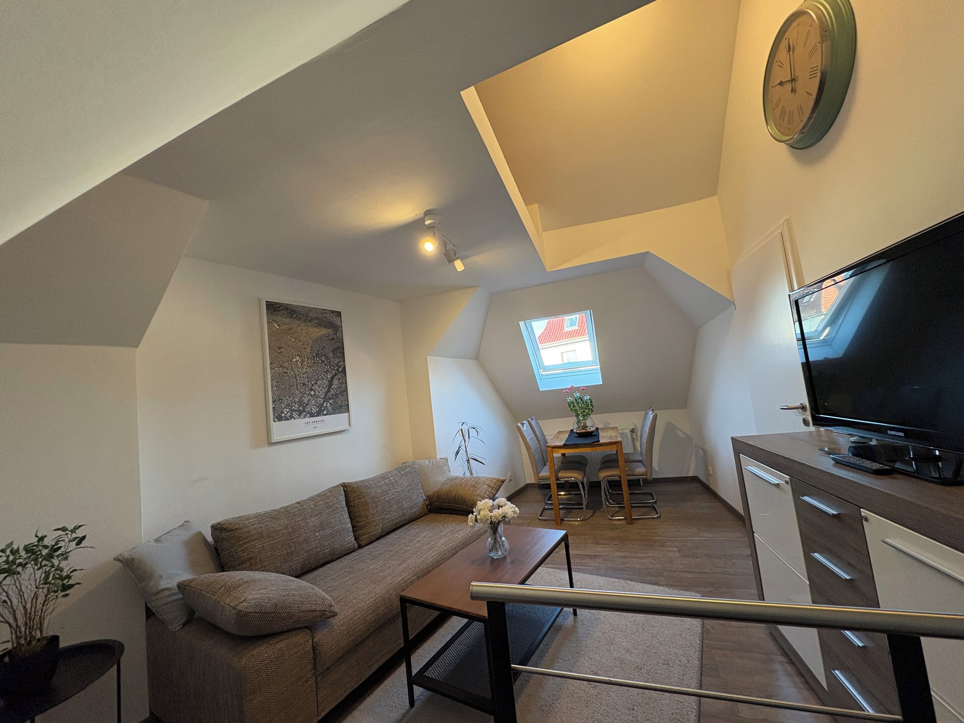 Ein kompakter Wohnraum mit Sofa, Couchtisch, Fernseher und Essbereich mit Stühlen und Tisch.