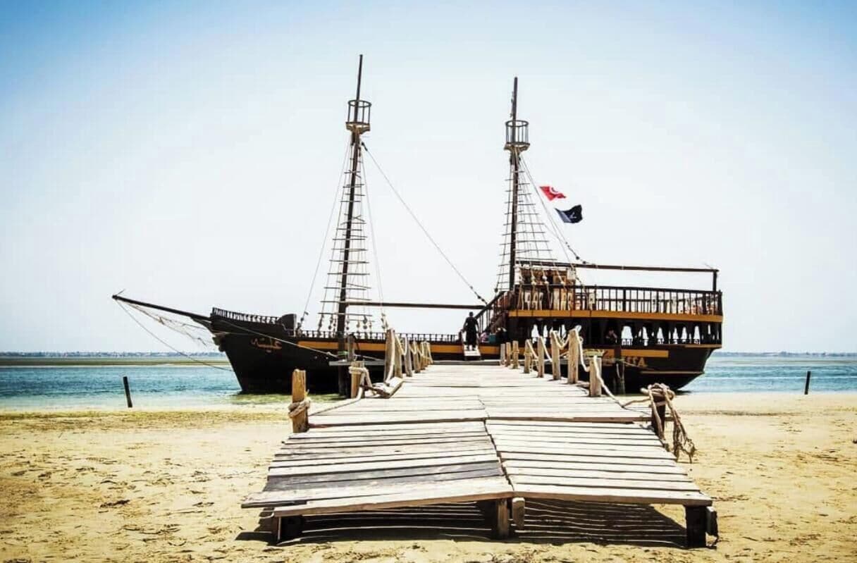 Two large ships docked on a sandy beach with a clear sky in the background.