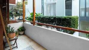 Un balcón con barandilla de madera, plantas en macetas y un tapiz estampado.