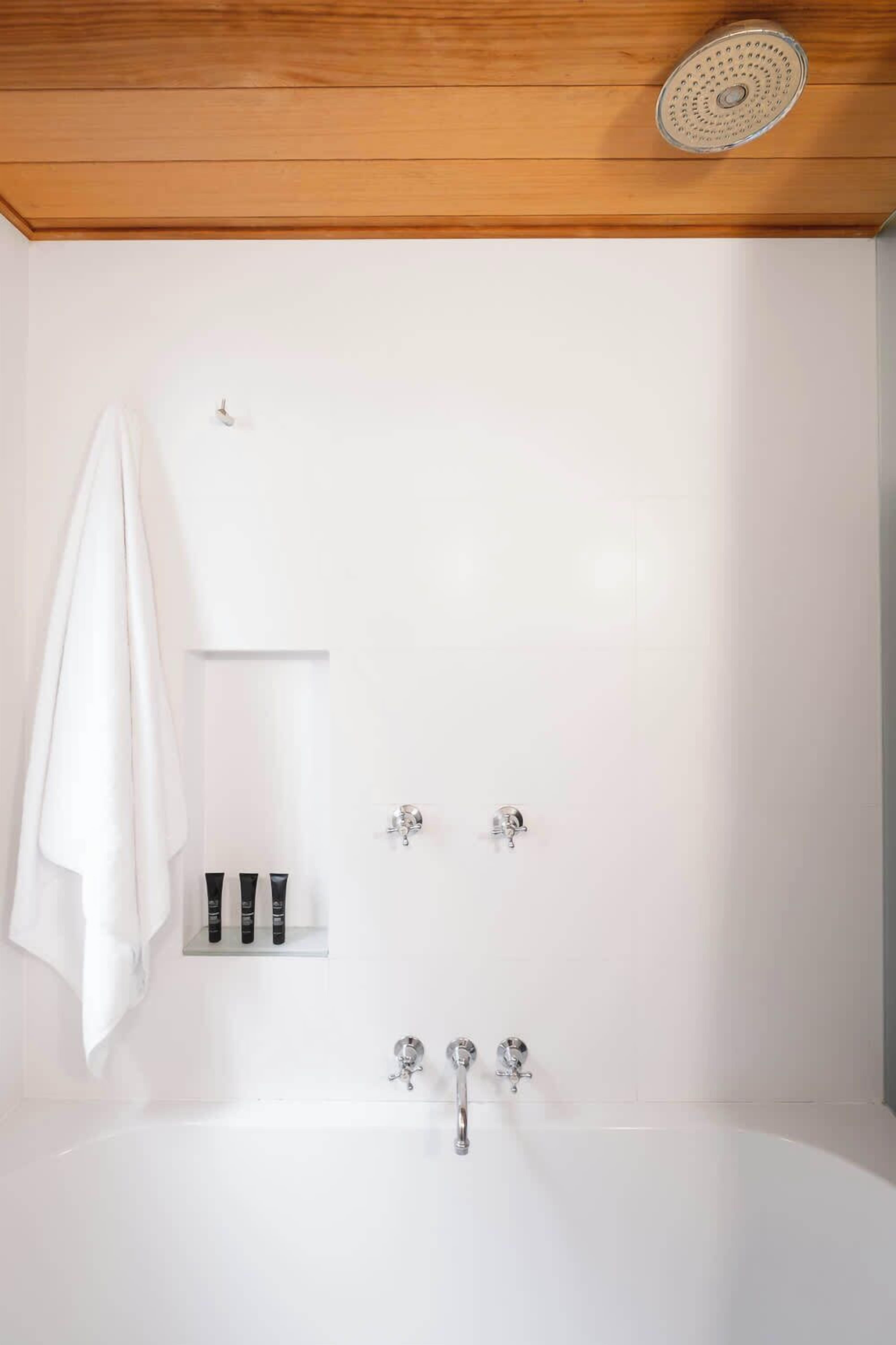 A modern bathroom with a freestanding bathtub, a towel hanging on the wall, and a shelf with toiletries.