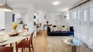 Un espacio habitable moderno con comedor, cocina y una zona de estar acogedora con sofá y mesa de centro.