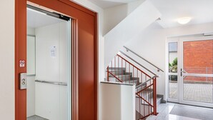 An interior view of a hotel lobby with a staircase, a door leading to an outdoor area, and a no-smoking sign. - Apartment 'Duhnen' with Balcony and Wi-Fi (Cuxhaven)