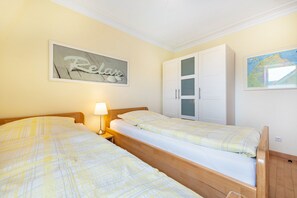 Une chambre avec deux lits, une carte accrochée au mur et une armoire.