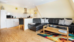 A modern living room with a black leather sofa, a wooden coffee table, and a colorful rug. - Apartment 'Duhnen' with Balcony and Wi-Fi (Cuxhaven)