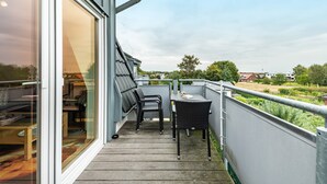 A balcony with a table and chairs, a glass door, and a view of the surrounding area. - Apartment 'Duhnen' with Balcony and Wi-Fi (Cuxhaven)