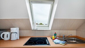 A kitchen with a skylight, a stove, a sink, and a coffee maker.