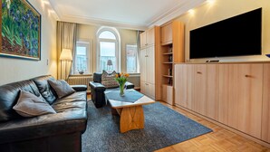 A living room with a sofa, coffee table, TV, and wooden cabinets.