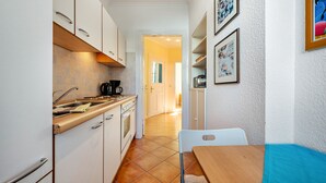 A compact kitchen with white cabinets, a wooden countertop, and a dining area with a table and chairs. - Apartment '4' with Wi-Fi (Cuxhaven)