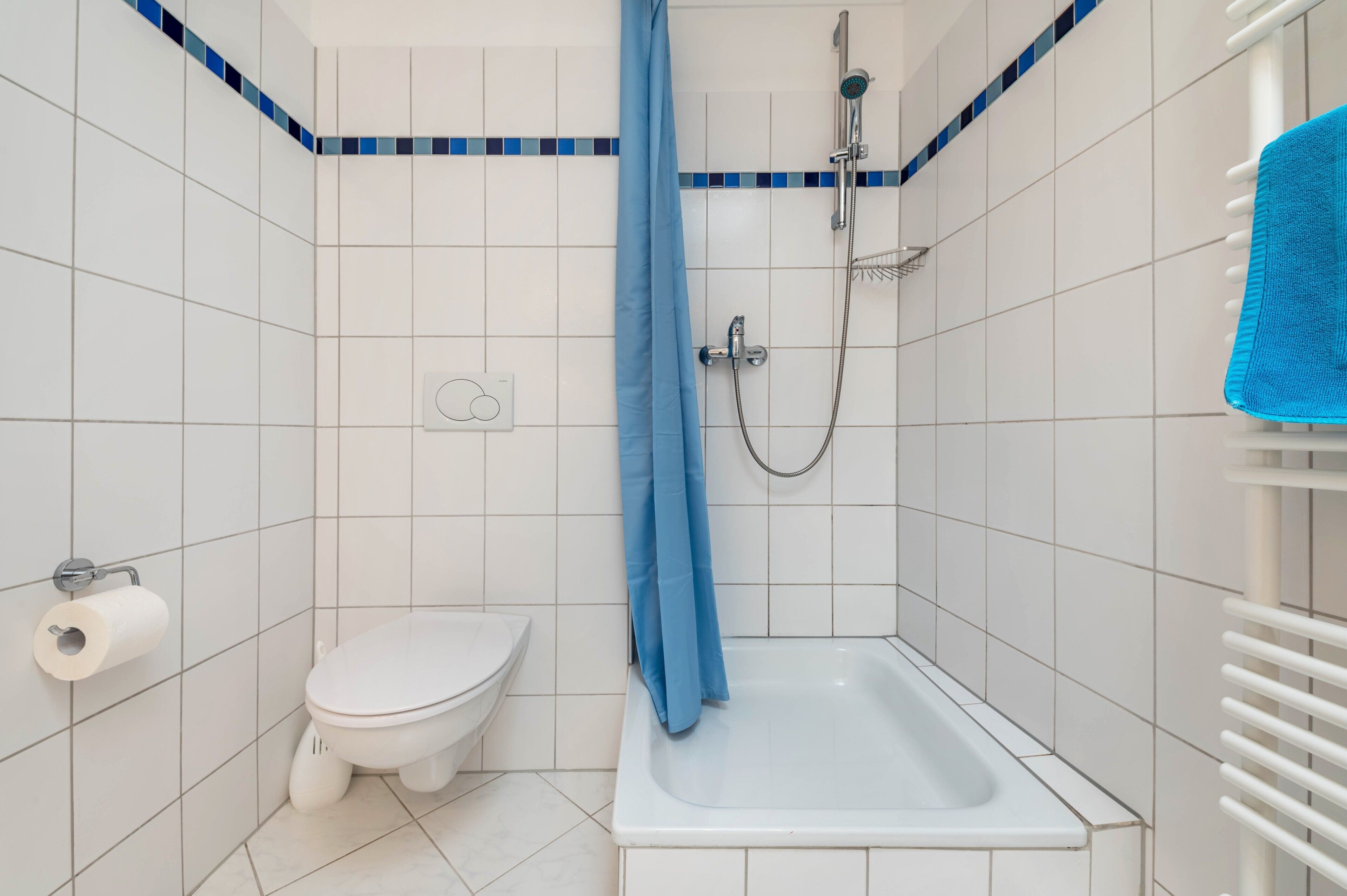 Une petite salle de bain comprenant des toilettes, une douche et un porte-serviettes.