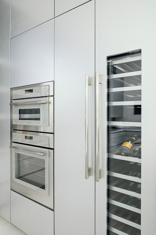 A kitchen with built-in stainless steel appliances, including a double oven and a refrigerator with a glass door.