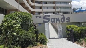 A multi-story hotel with a curved facade, a sign reading "THE Sands," and a gated entrance. - The Sands Beachfront city centre (Surfers Paradise)